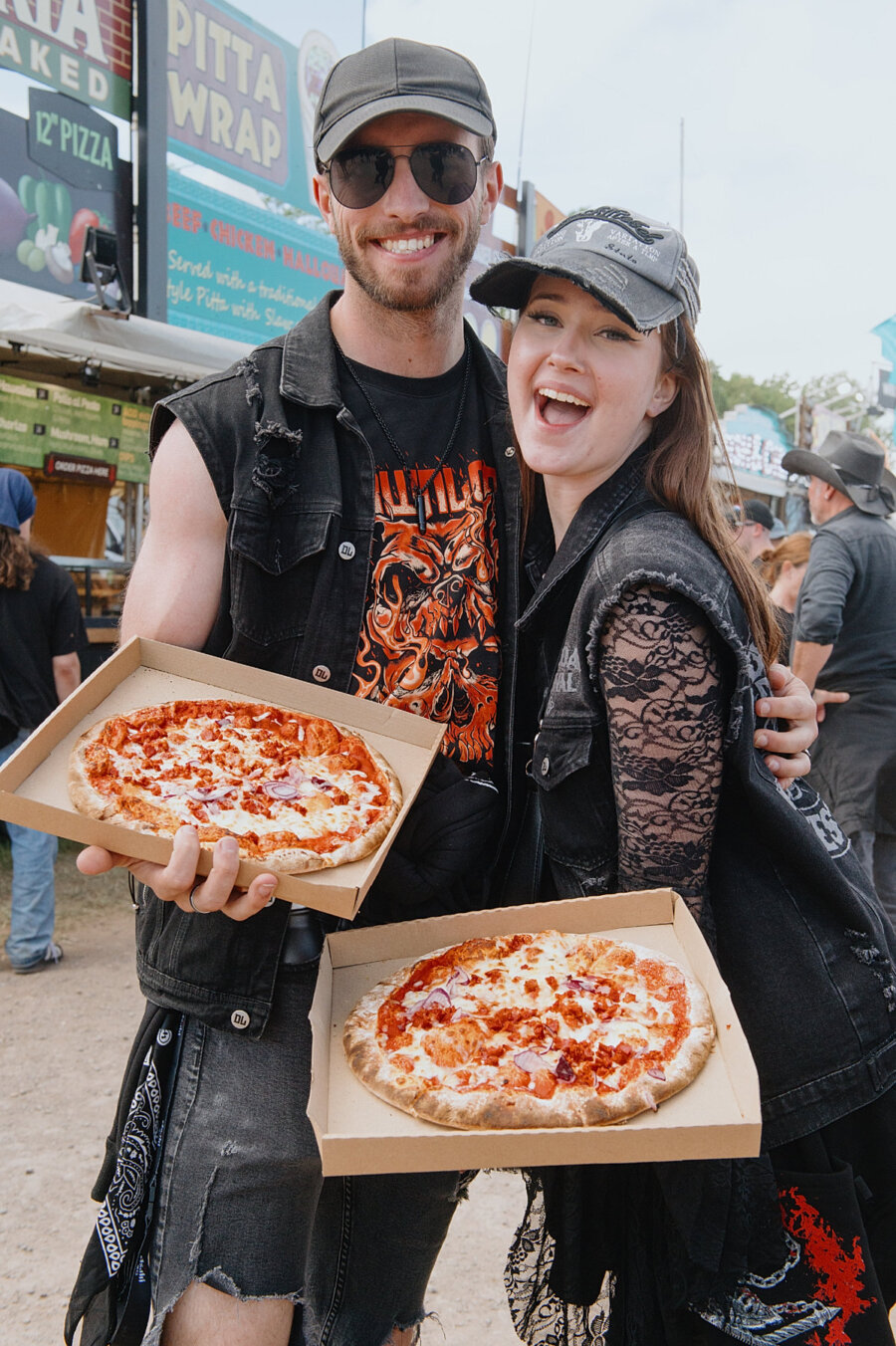 Image shows 2 Download fans smiling holding pizza boxes. 