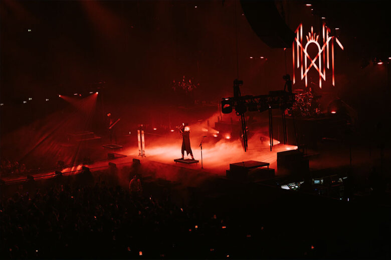 Sleep Token on a red-lit stage performing in front of a crowd