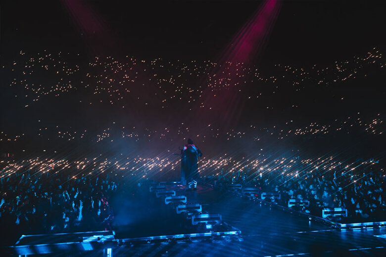 Sleep Token performing on stage in front of a dimly lit crowd