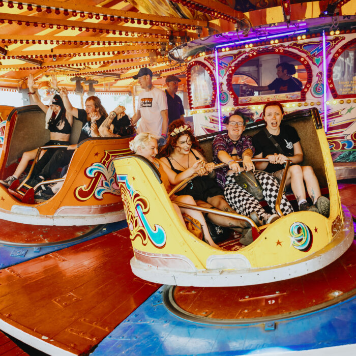Download fans riding the waltzer (funfair ride) in District X.