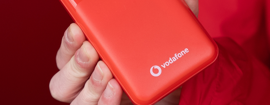A red vodafone power bank held by a person facing the camera.